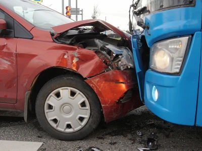 Red car and blue truck involved in a head-on collision, with significant front-end damage to the red vehicle and debris on the road.