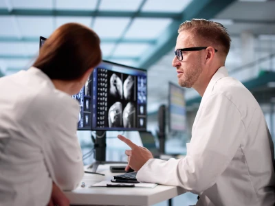 Medical professionals analyzing brain scan images on a monitor in a modern clinical setting.