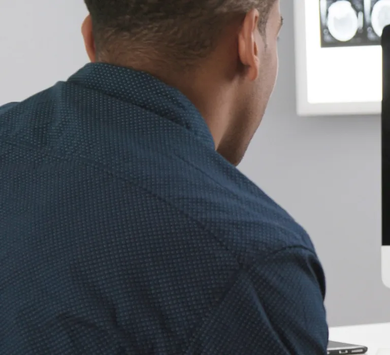 A doctor showing a patient brain scan images on a computer screen in a medical office setting.