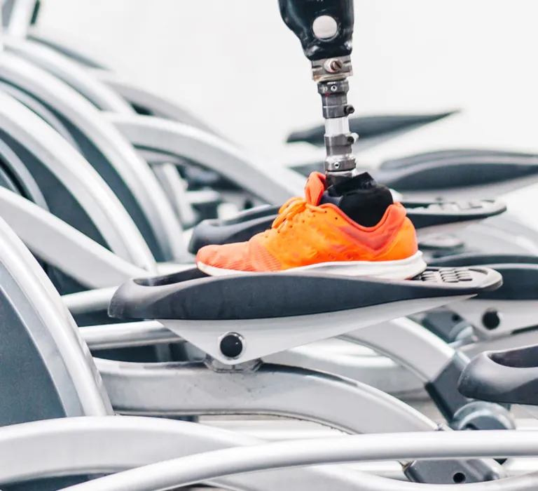 Person running on an elliptical machine in a gym with multiple elliptical trainers in the background.