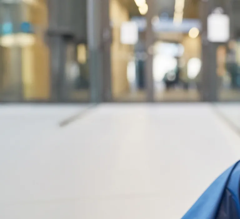 A healthcare worker in blue scrubs, a mask, and a cap sitting on the floor with his hands covering his face, appearing distressed or exhausted.